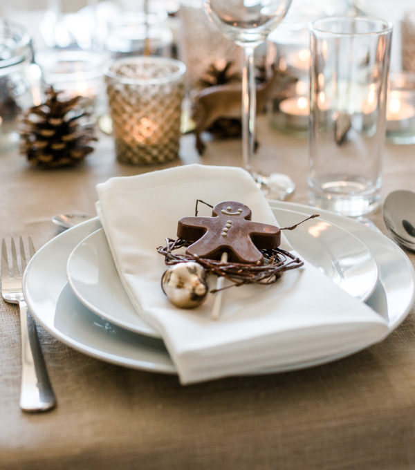 Weihnachtliche Tischdekoration mit Kerzen und Lebkuchenmann aus Schokolade